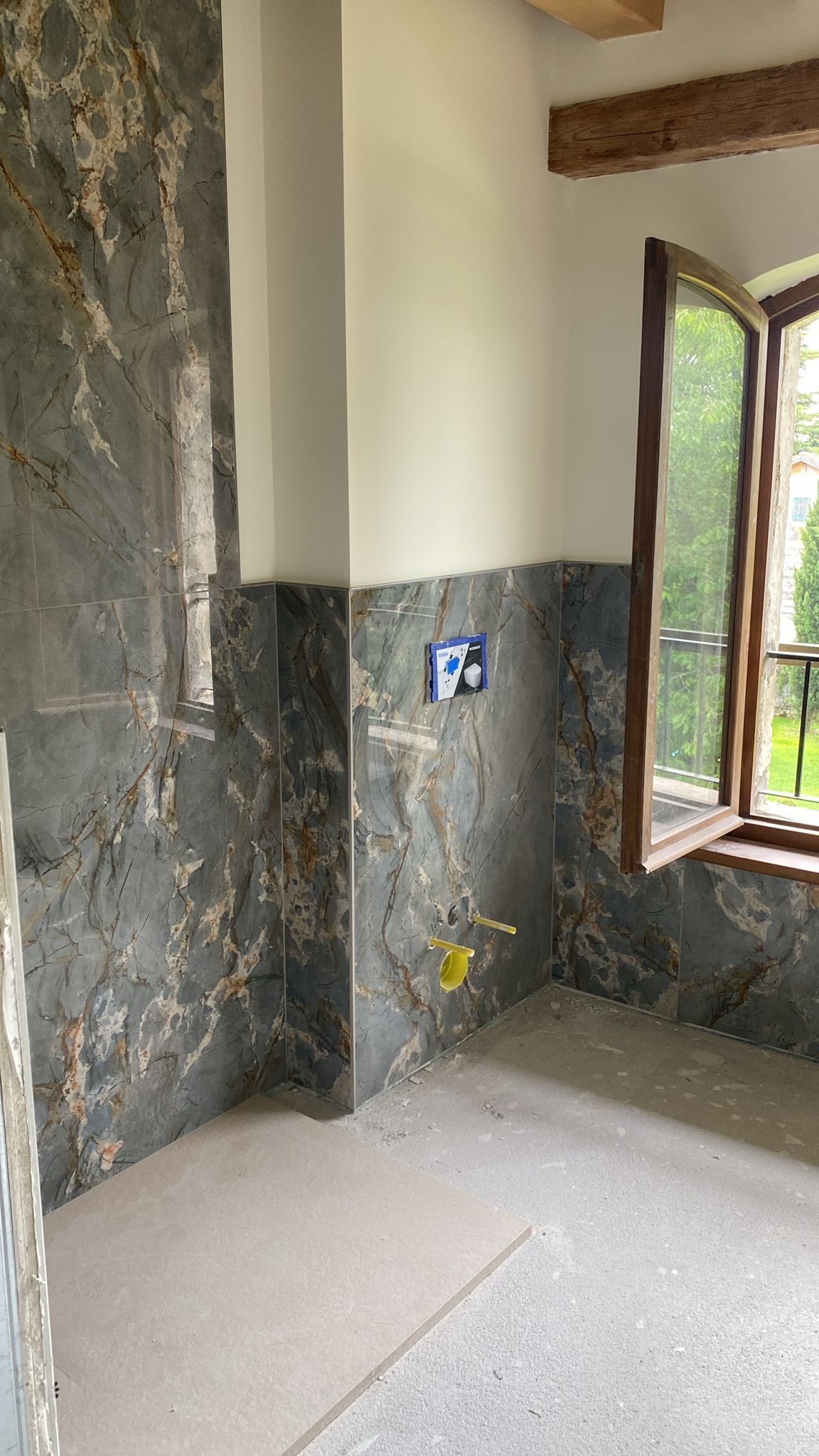 Un bagno con finestra e parete di marmo.