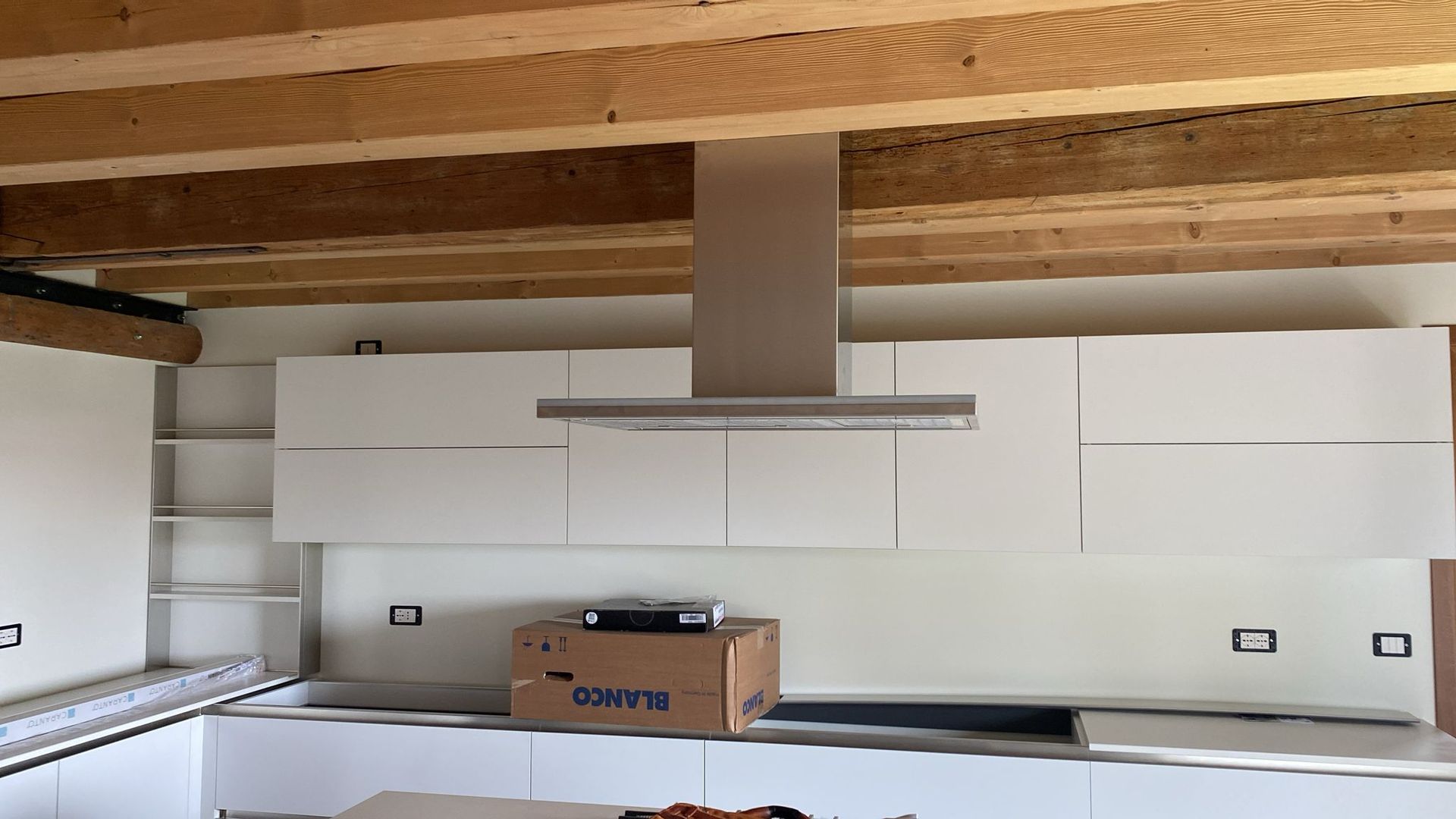 Una cucina con mobili bianchi e una scatola con la scritta Iveco sopra