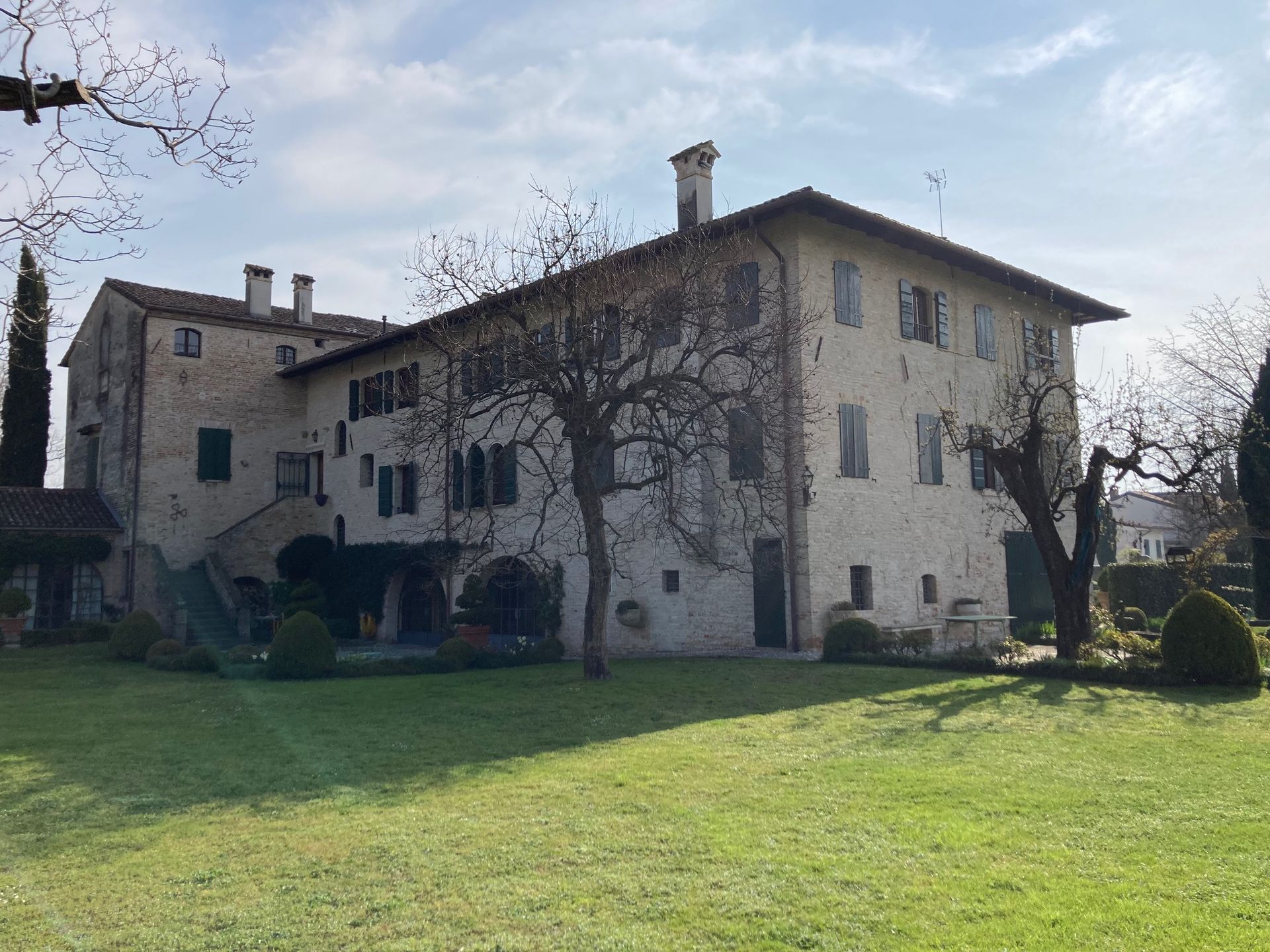 Una grande casa con molte finestre è circondata da alberi ed erba