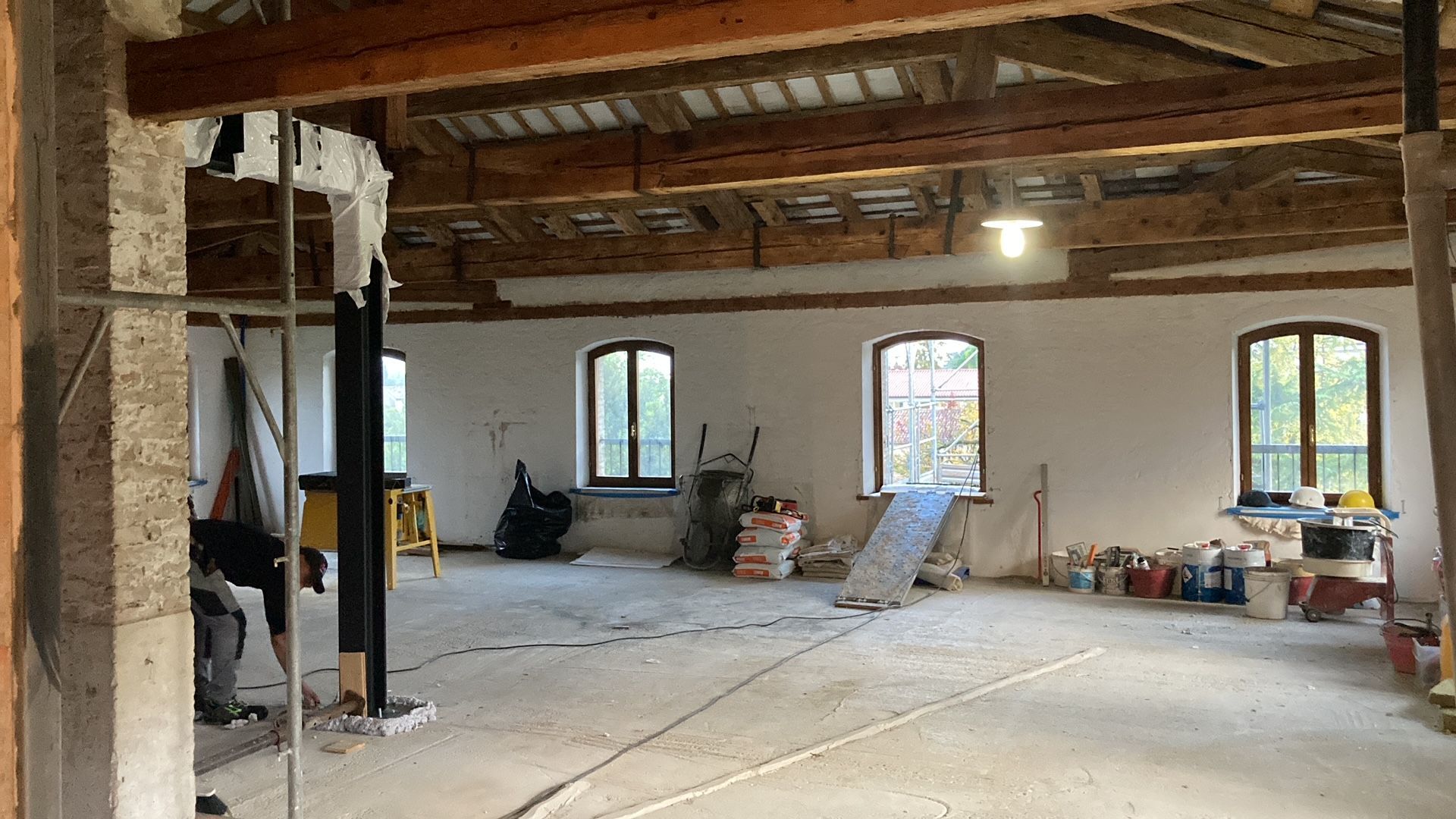 Una grande stanza con molte finestre e travi in legno.