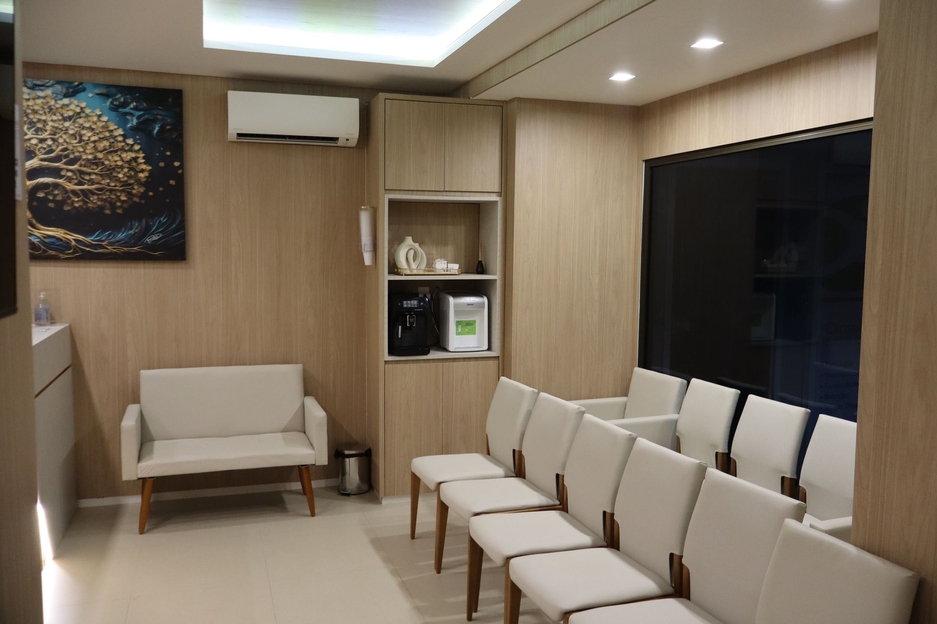 A waiting room with a couch and chairs and a painting on the wall.