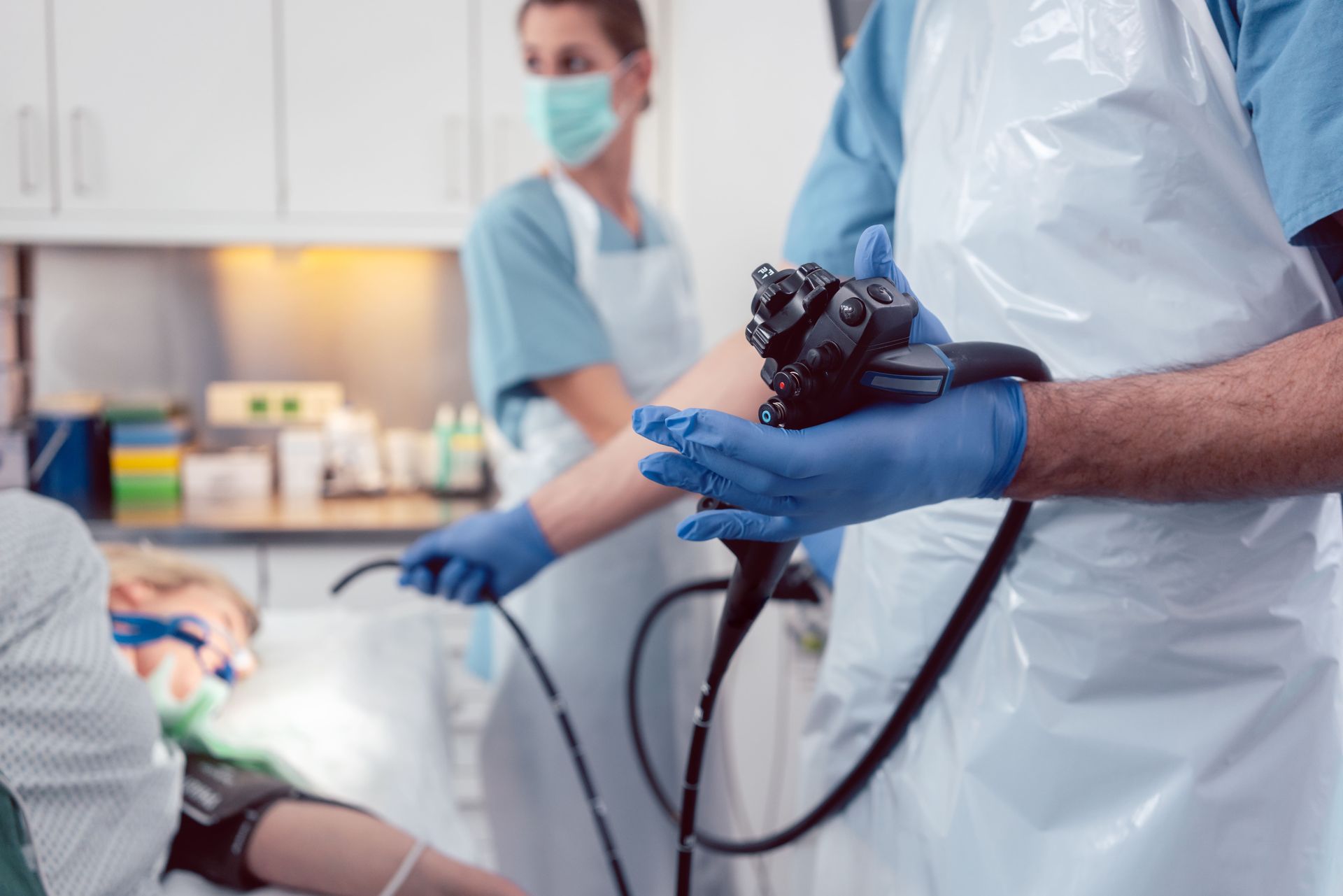 A doctor is holding an endoscope in front of a patient.