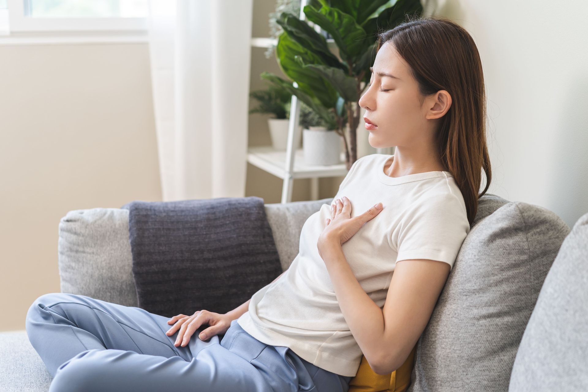A woman is sitting on a couch with her eyes closed.