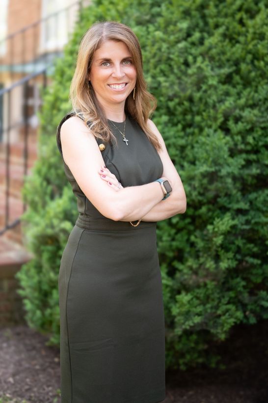 A woman wearing a black shirt and a necklace is smiling for the camera.