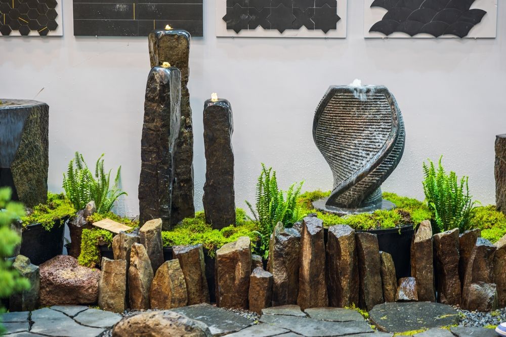 Water fountain display with stone sculptures and greenery.