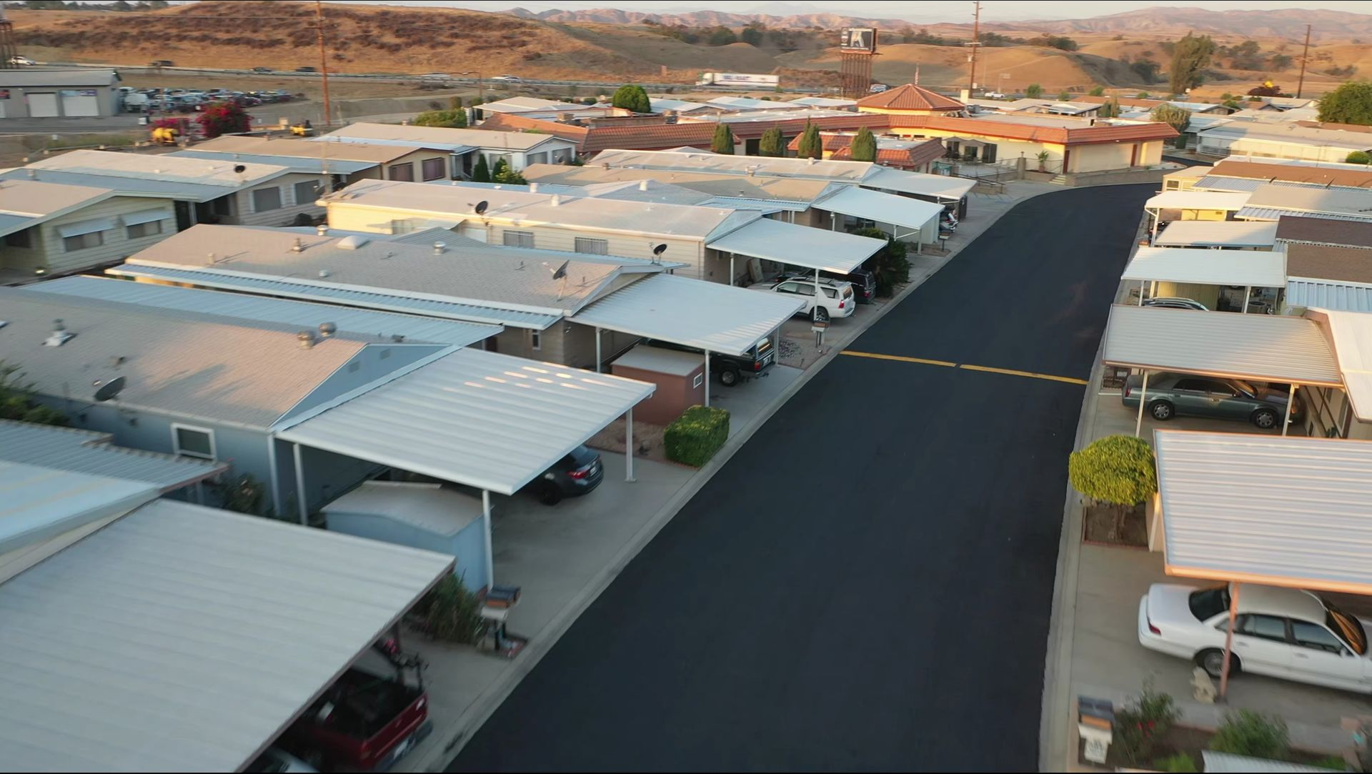 Aerial view of a quiet residential street with rows of carports and houses on both sides.