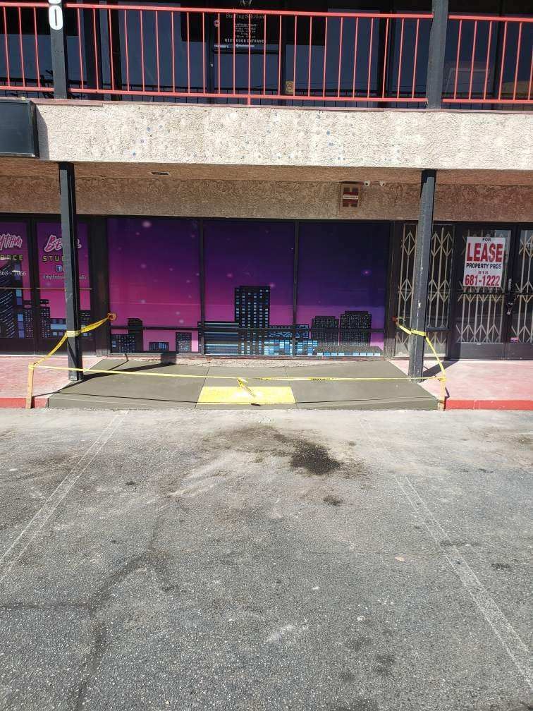 Storefront entrance with yellow ramp, purple windows, and “LEASE” sign behind caution tape