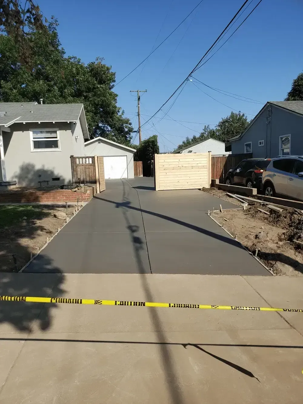 Police tape blocking a residential driveway with a boarded-up garage and parked truck nearby
