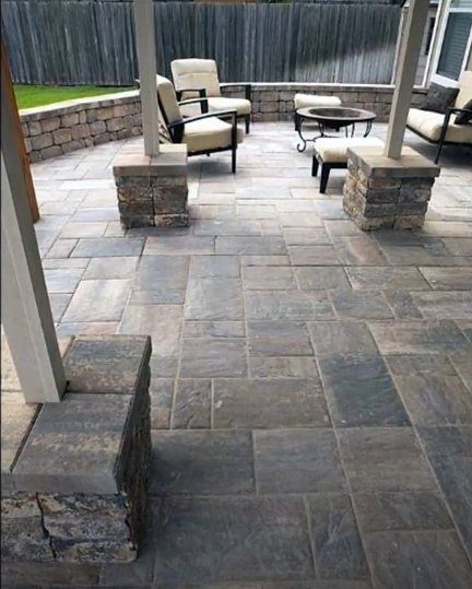 New backyard patio with a stamped concrete design.  The patio has a roof with pillars.  There is outdoor furniture and a firepit.