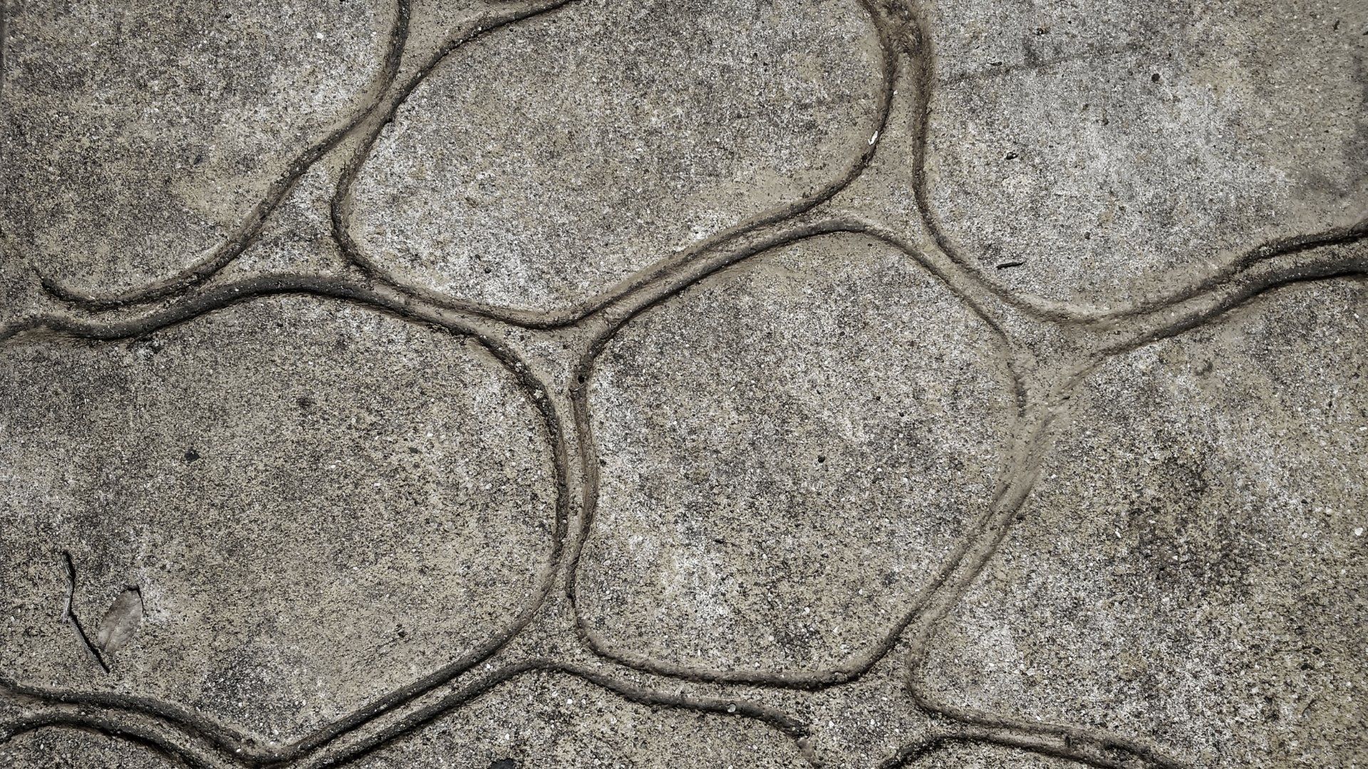 Close up picture of a grey stamped concrete design with circular patterns.