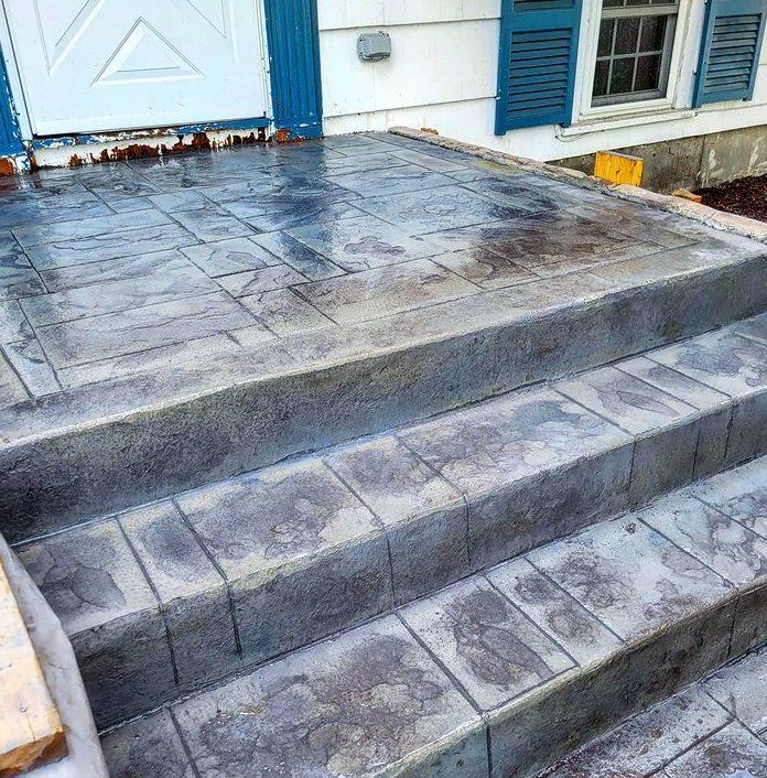 Freshly poured stamped concrete steps leading up to a back door of a house.