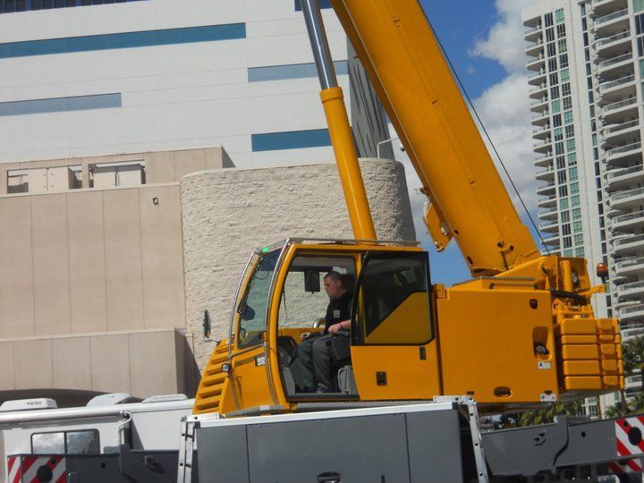 a man is driving a large yellow crane in front of a building