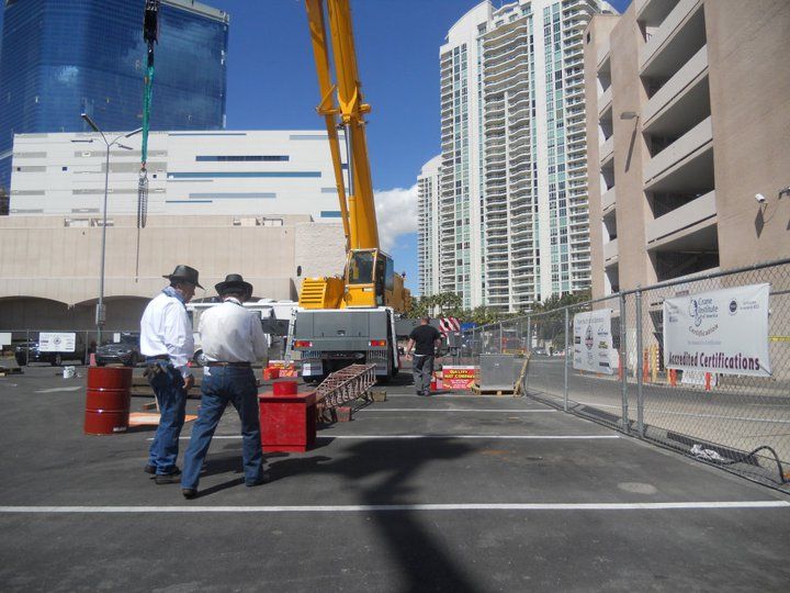 two men are standing in front of a crane in a parking lot