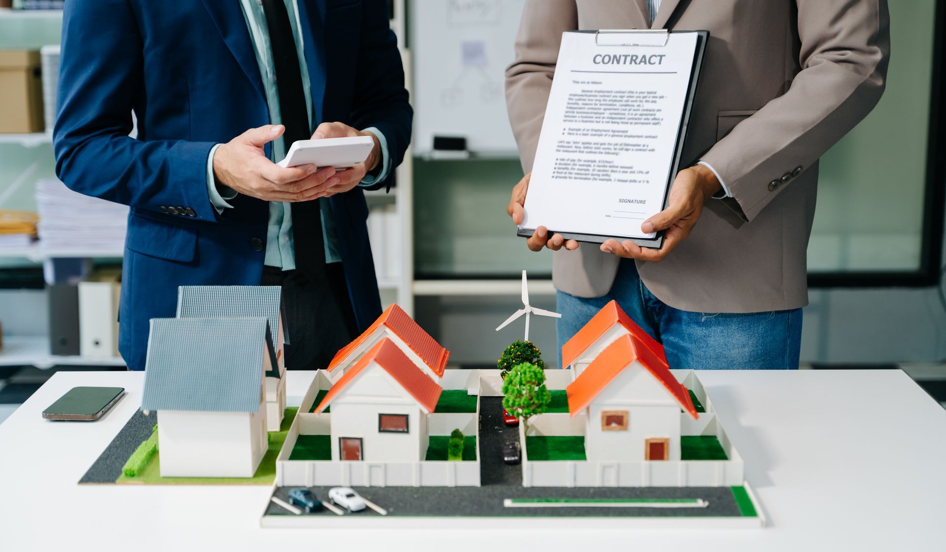 A man and a woman are standing next to a model of a house.