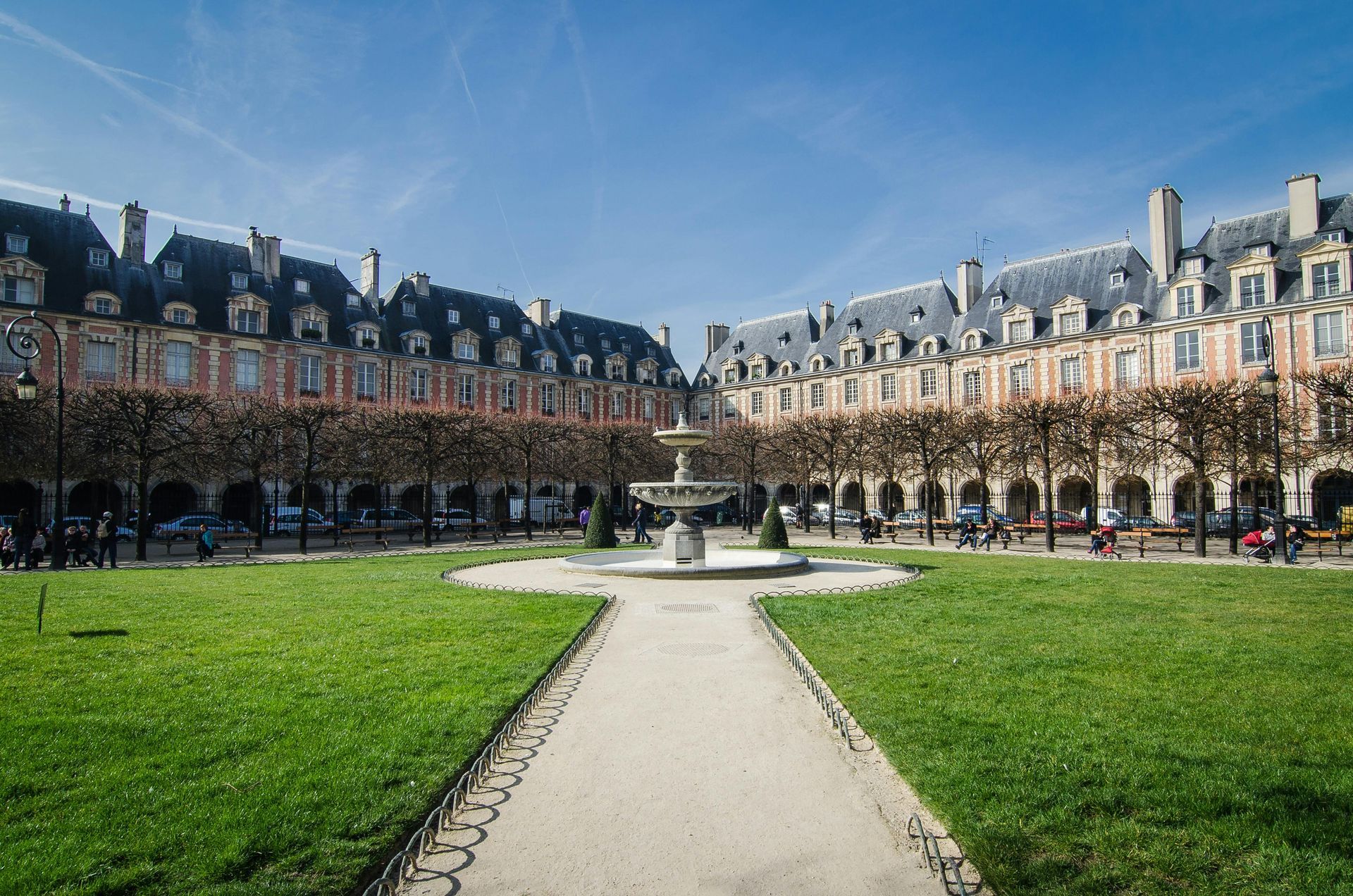 Courtyard with buildings, fountain, and trees under a clear blue sky.