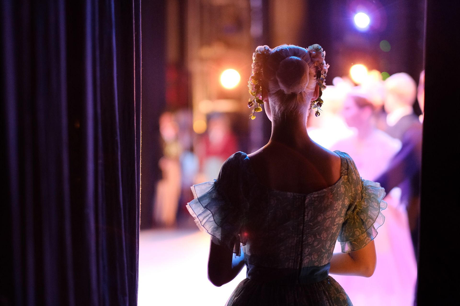 A woman in a blue dress is standing in front of a stage.