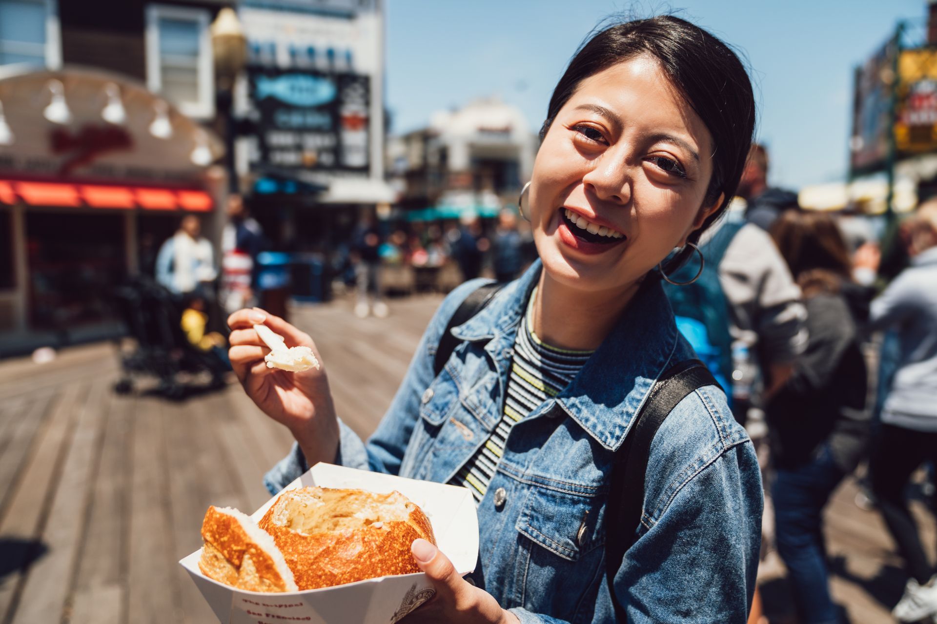 A woman is eating on a pier.