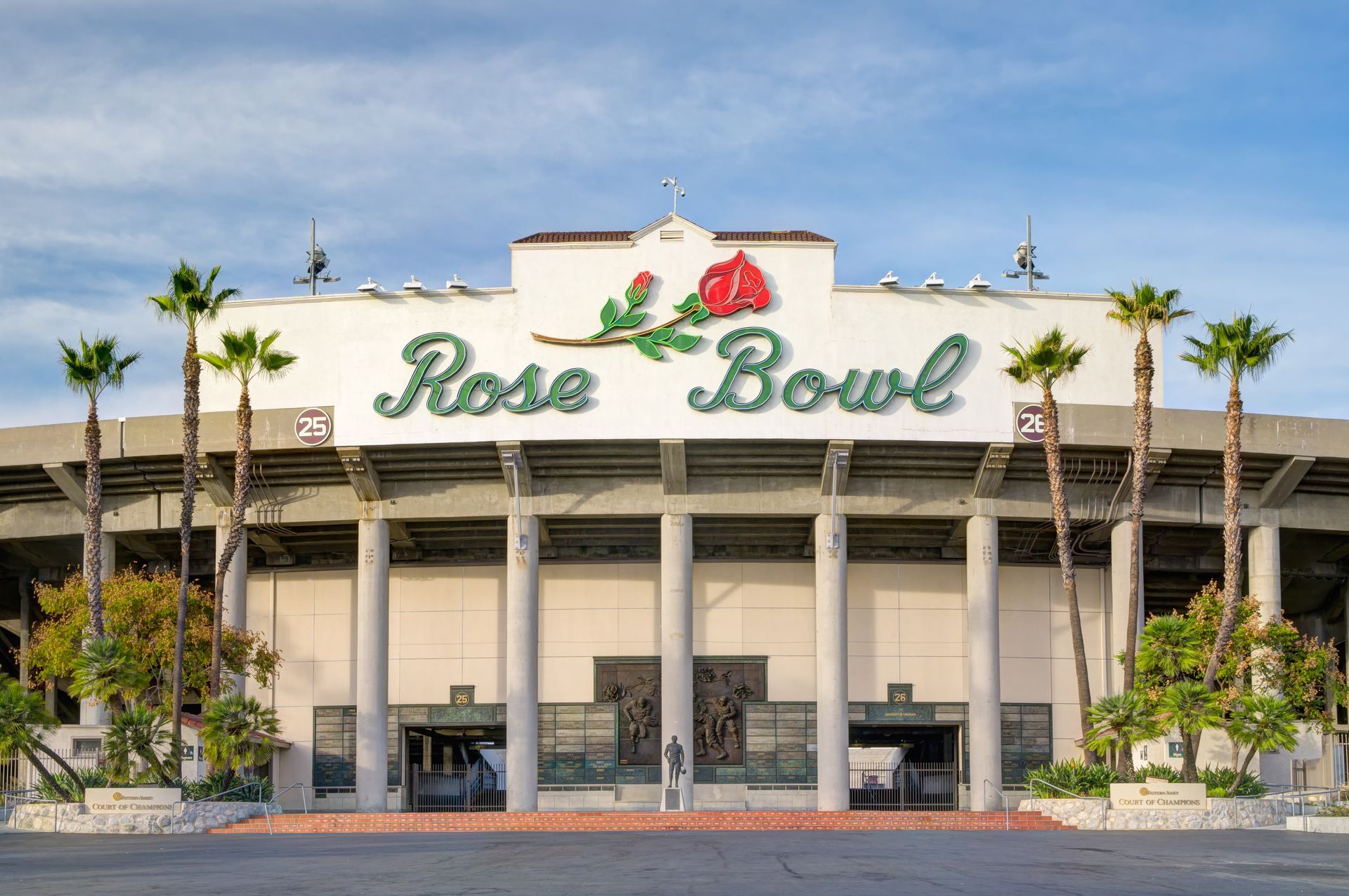 The front of the rose bowl stadium with palm trees in front of it.