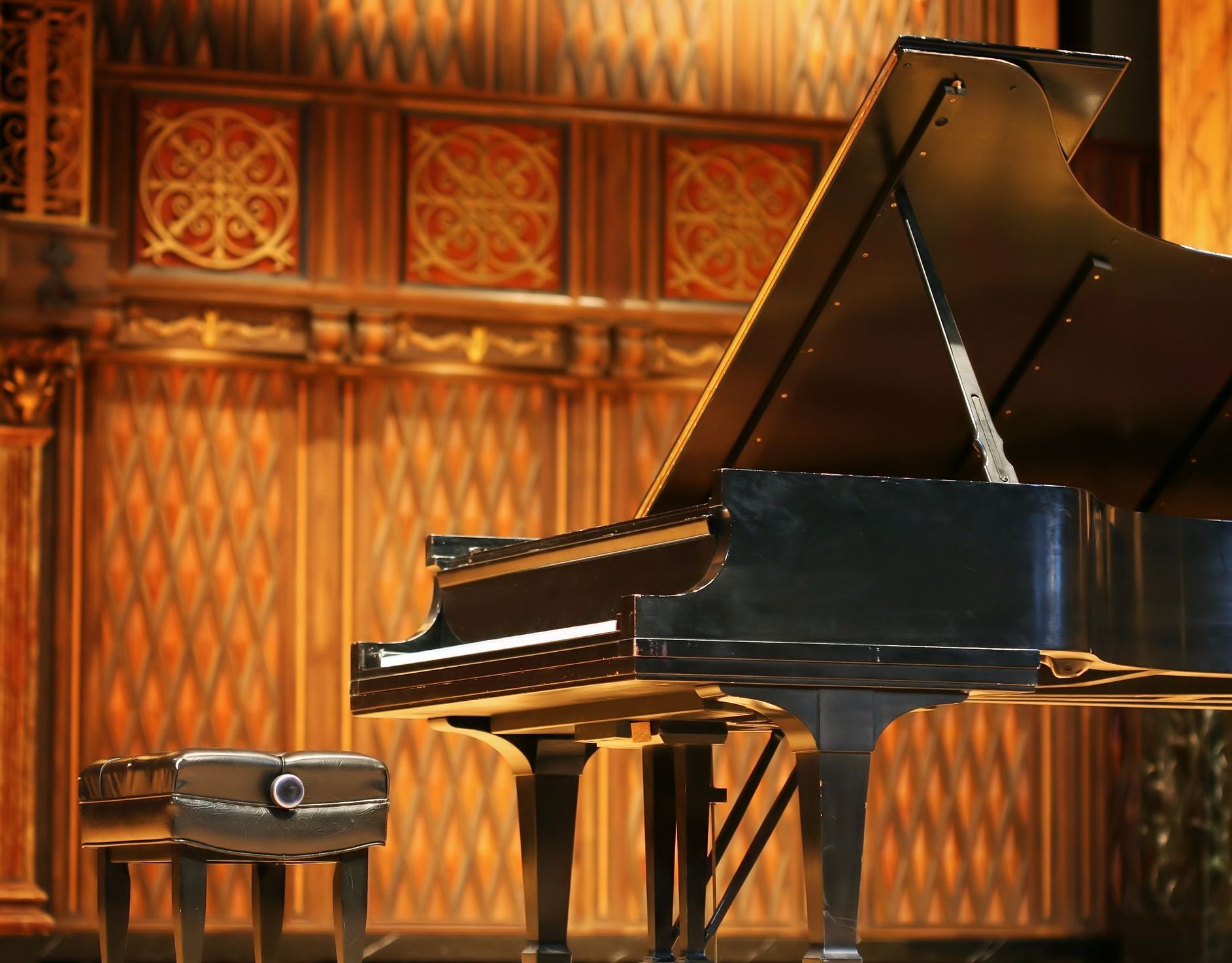 A piano is sitting on a stage with a stool in front of it