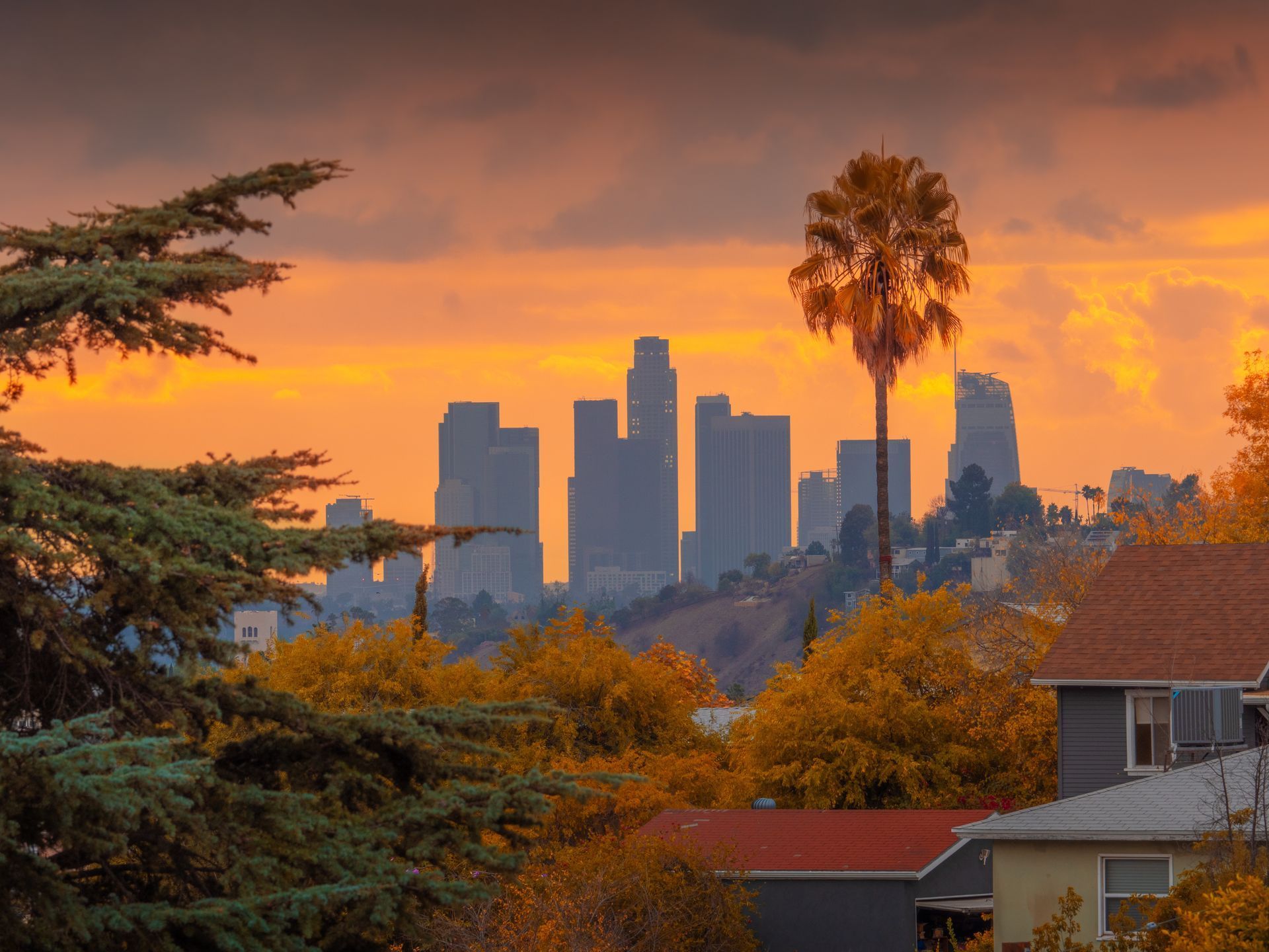 A sunset over a city skyline with a house in the foreground.