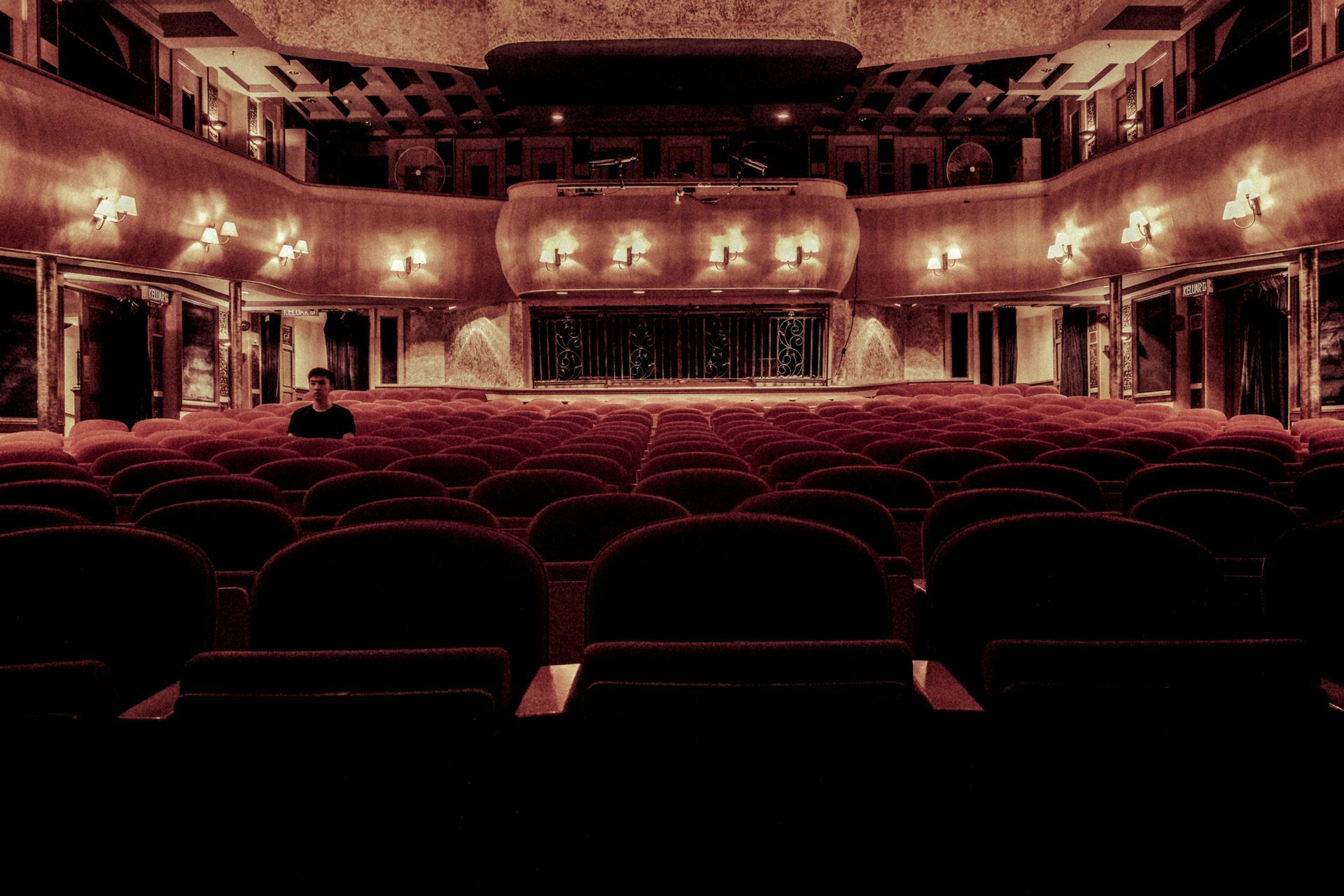 A large empty auditorium with red seats and a stage.