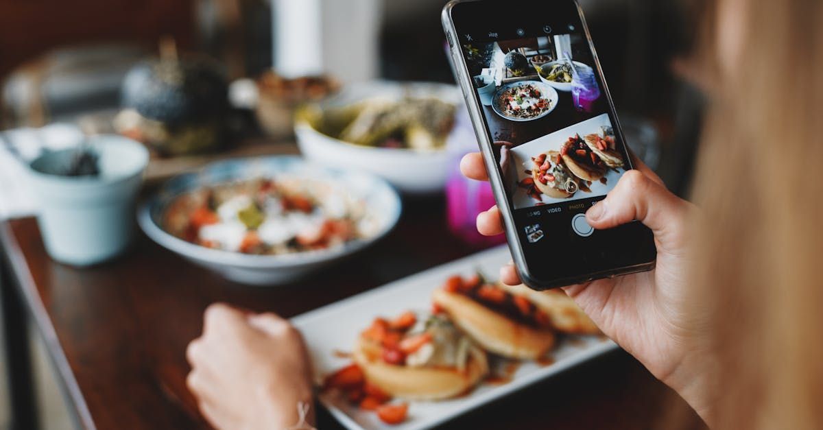 A person is taking a picture of a plate of food with a cell phone.