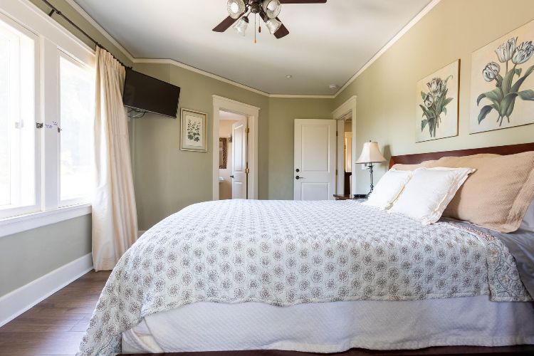 A bedroom with a king size bed and a ceiling fan.