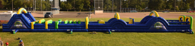 A large inflatable obstacle course is sitting on top of a lush green field.