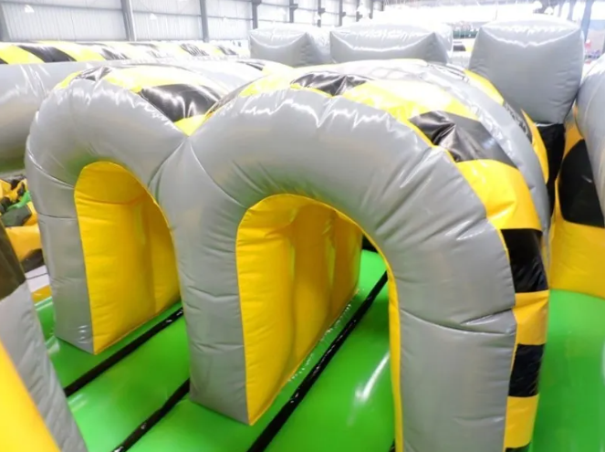 A yellow and gray inflatable Full Throttle obstacles with black stripes