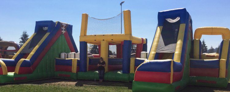 A man is standing in front of a large inflatable obstacle course.