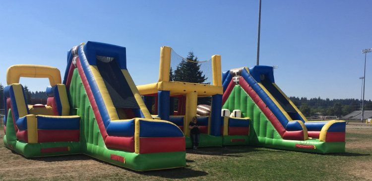 A large inflatable obstacle course is sitting on top of a lush green field.