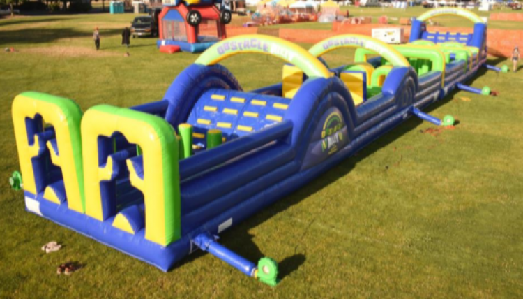 A large inflatable obstacle course is sitting on top of a lush green field.