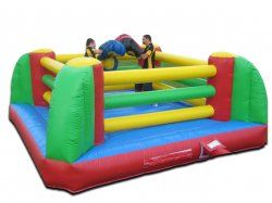A group of people are playing in an inflatable boxing ring.