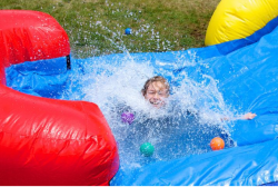 A little girl is playing in a water slide.