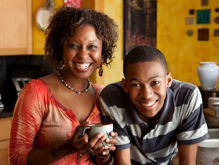 A woman is holding a cup of coffee next to a boy.