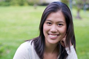 A woman is smiling for the camera with her hand on her chin.