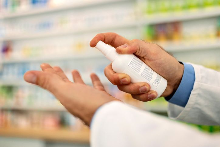 Un farmacista utilizza un disinfettante per pulirsi le mani in farmacia.