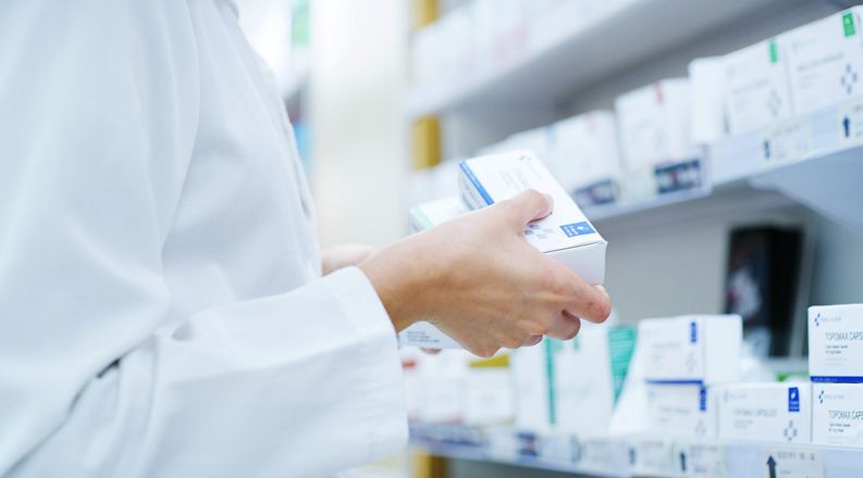 Un farmacista tiene in mano una scatola di pillole in una farmacia.