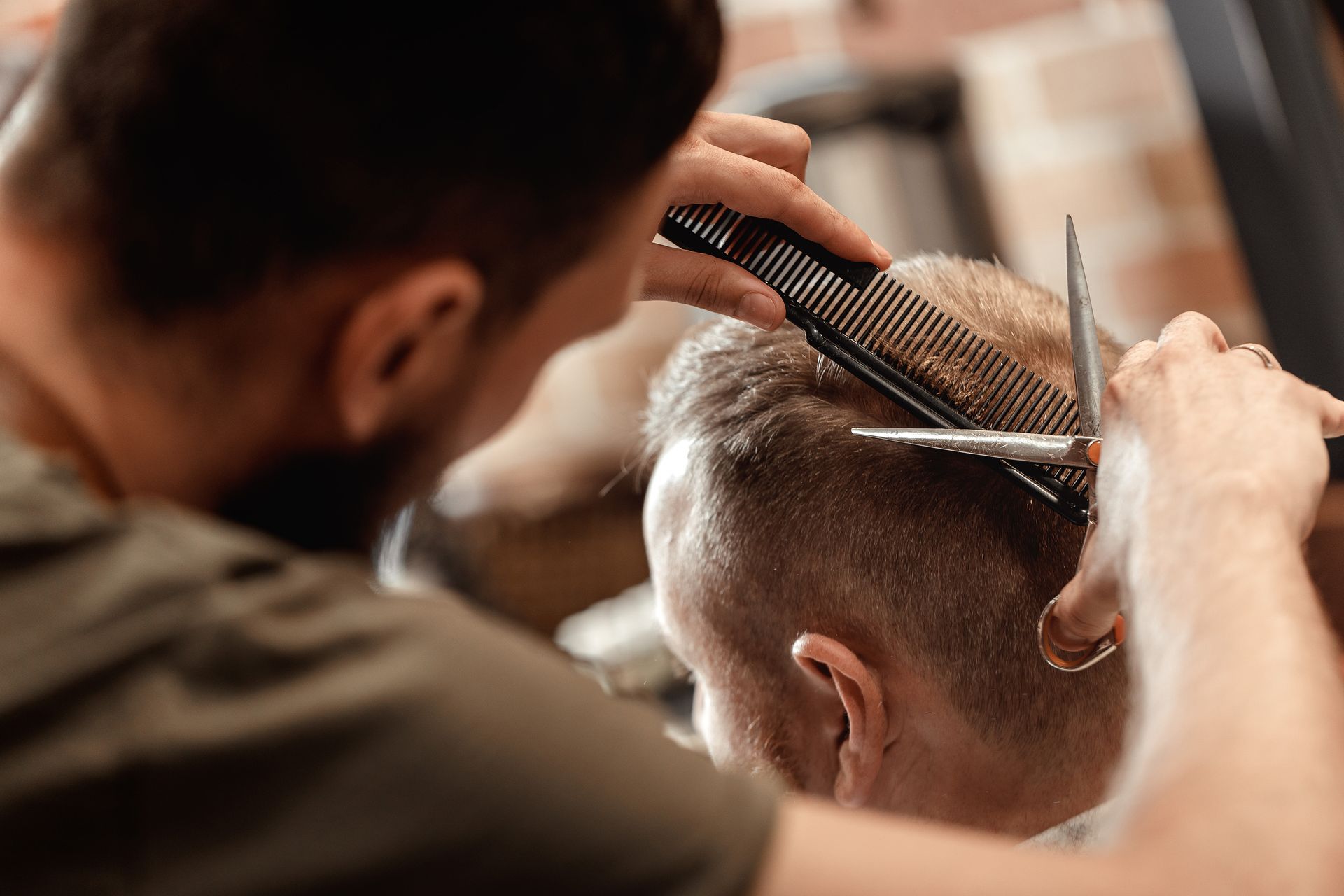A man is getting his hair cut by a barber in a barber shop.