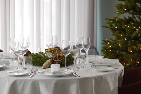 Bord med hvit duk, dekket og pyntet til julebord