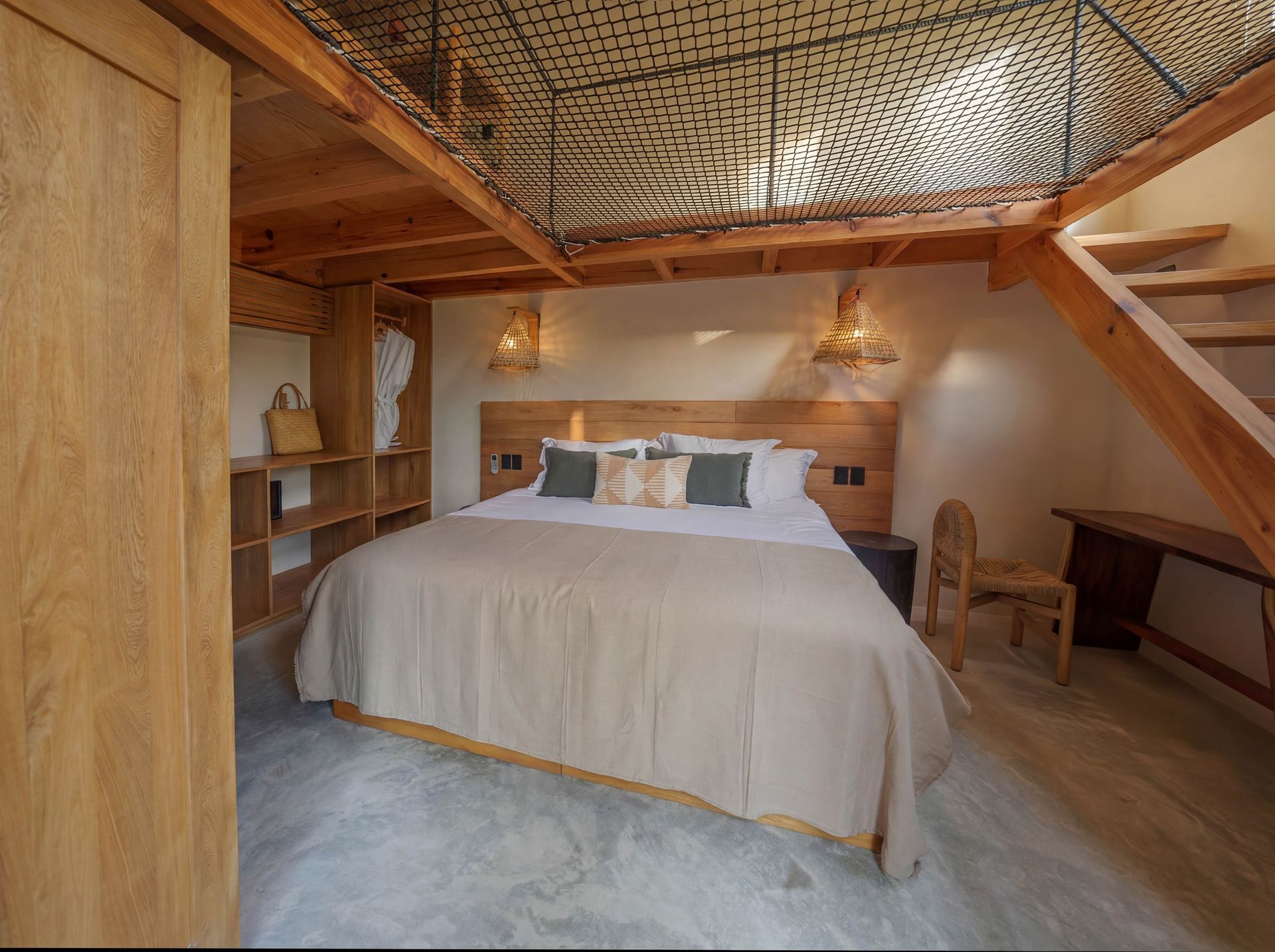 Cozy bedroom with a king bed, wood-paneled walls, ladder shelf, and carved ceiling detail.