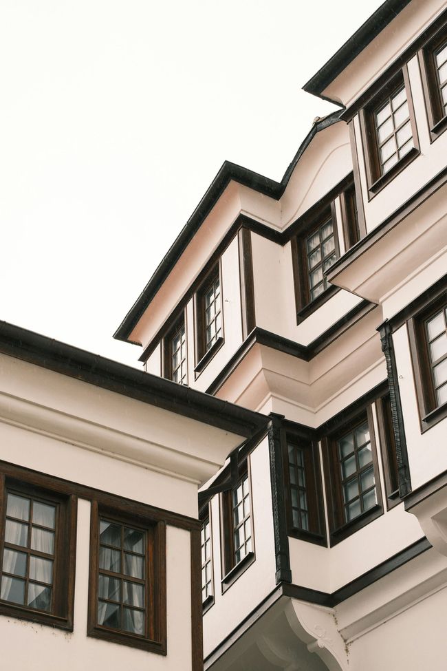 Close-up of white building facades with dark-trimmed windows against a bright sky