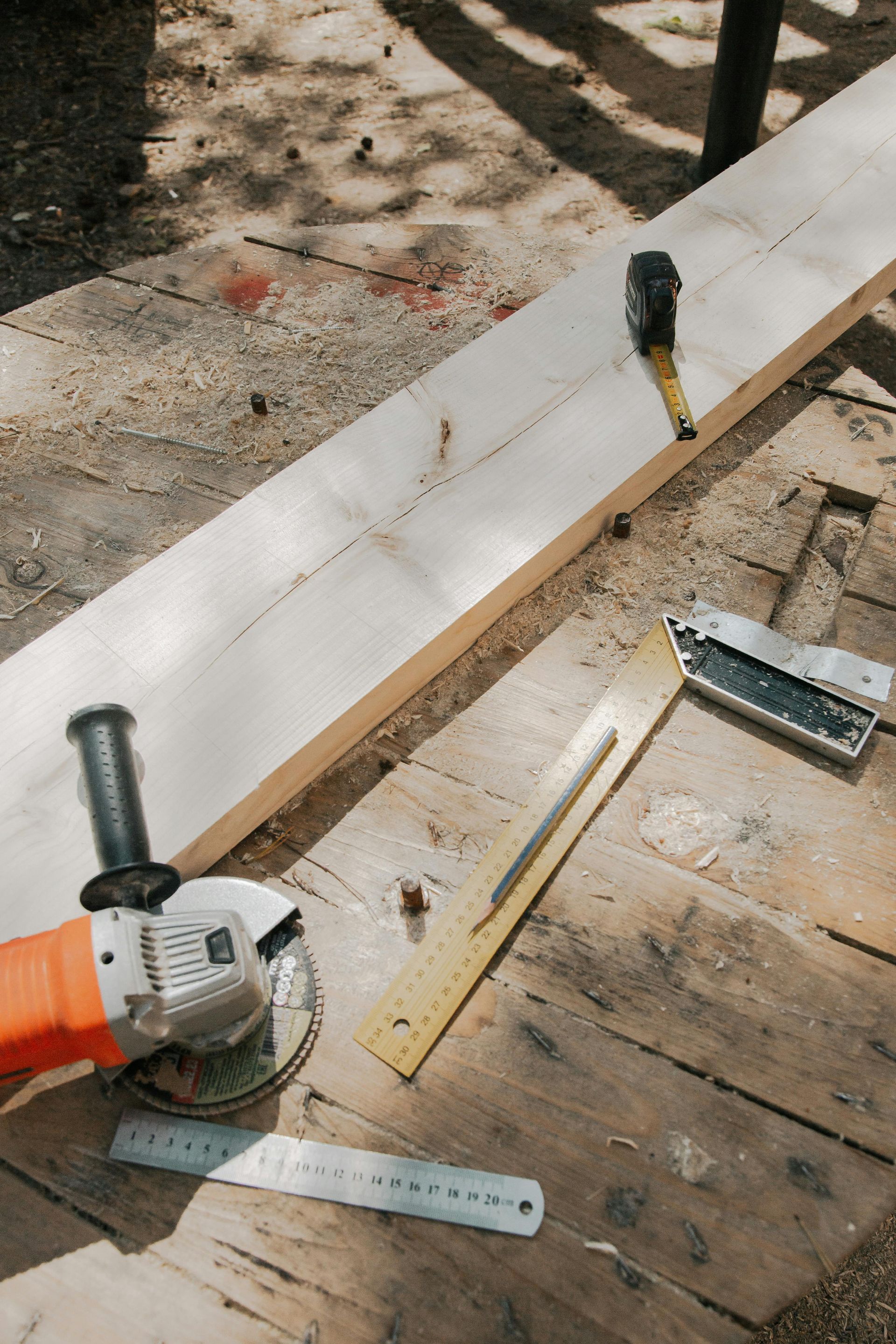 Tools and lumber on a workshop floor beside a white board under construction