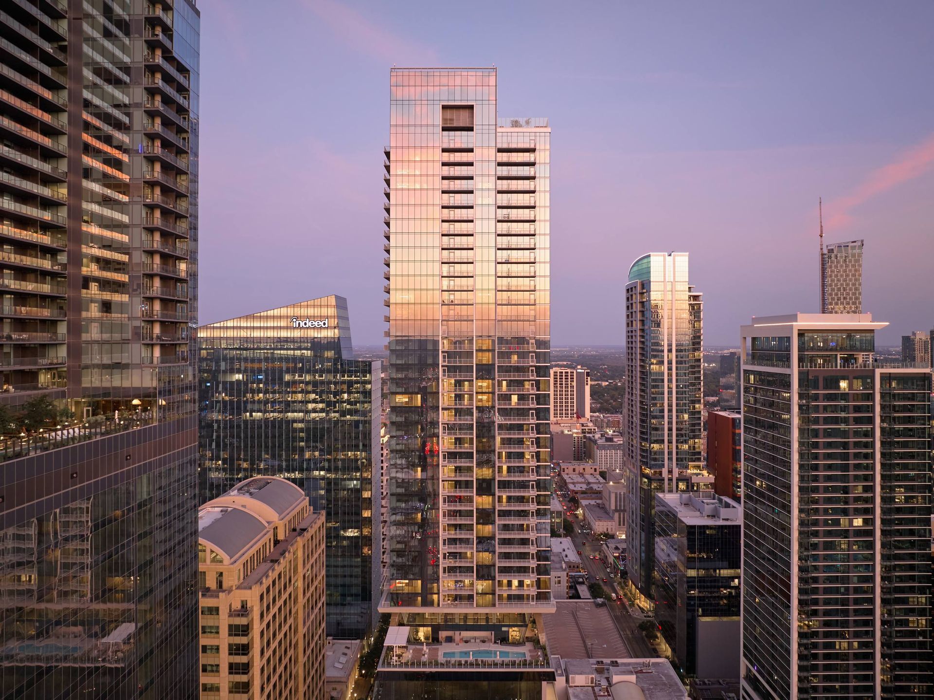 Skyscrapers in a city at sunset; buildings reflect the warm light.