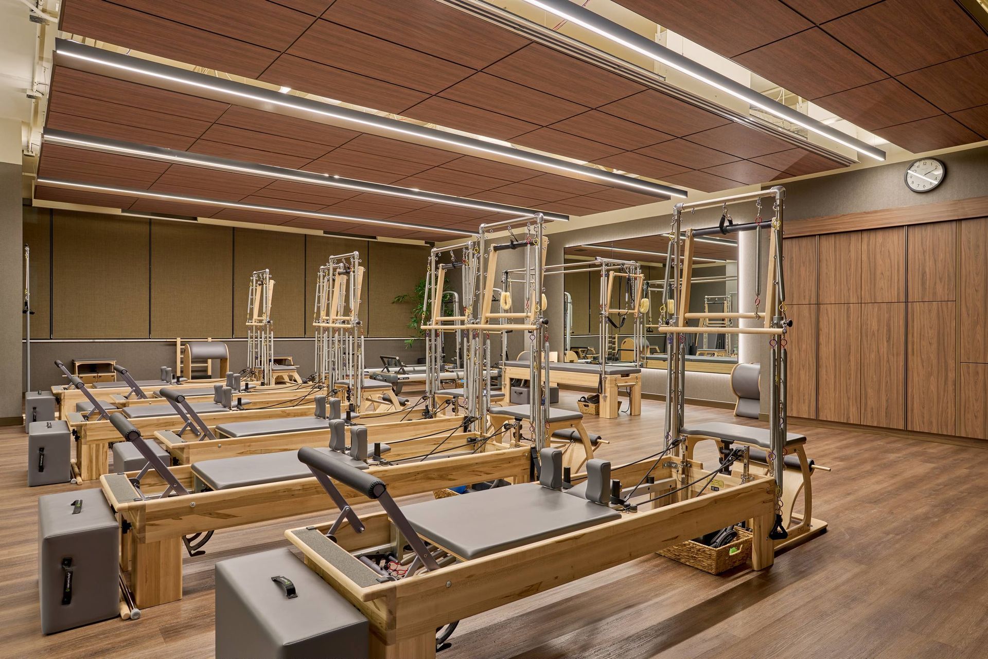 Pilates studio with wooden reformers, neutral tones, and warm lighting.