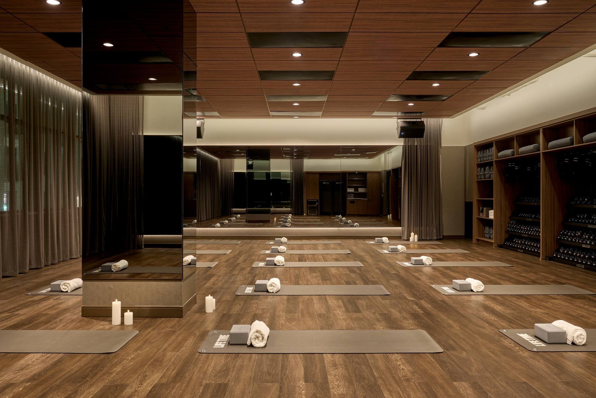 Yoga studio: wood floors, yoga mats, towels, mirrors, and storage shelves.