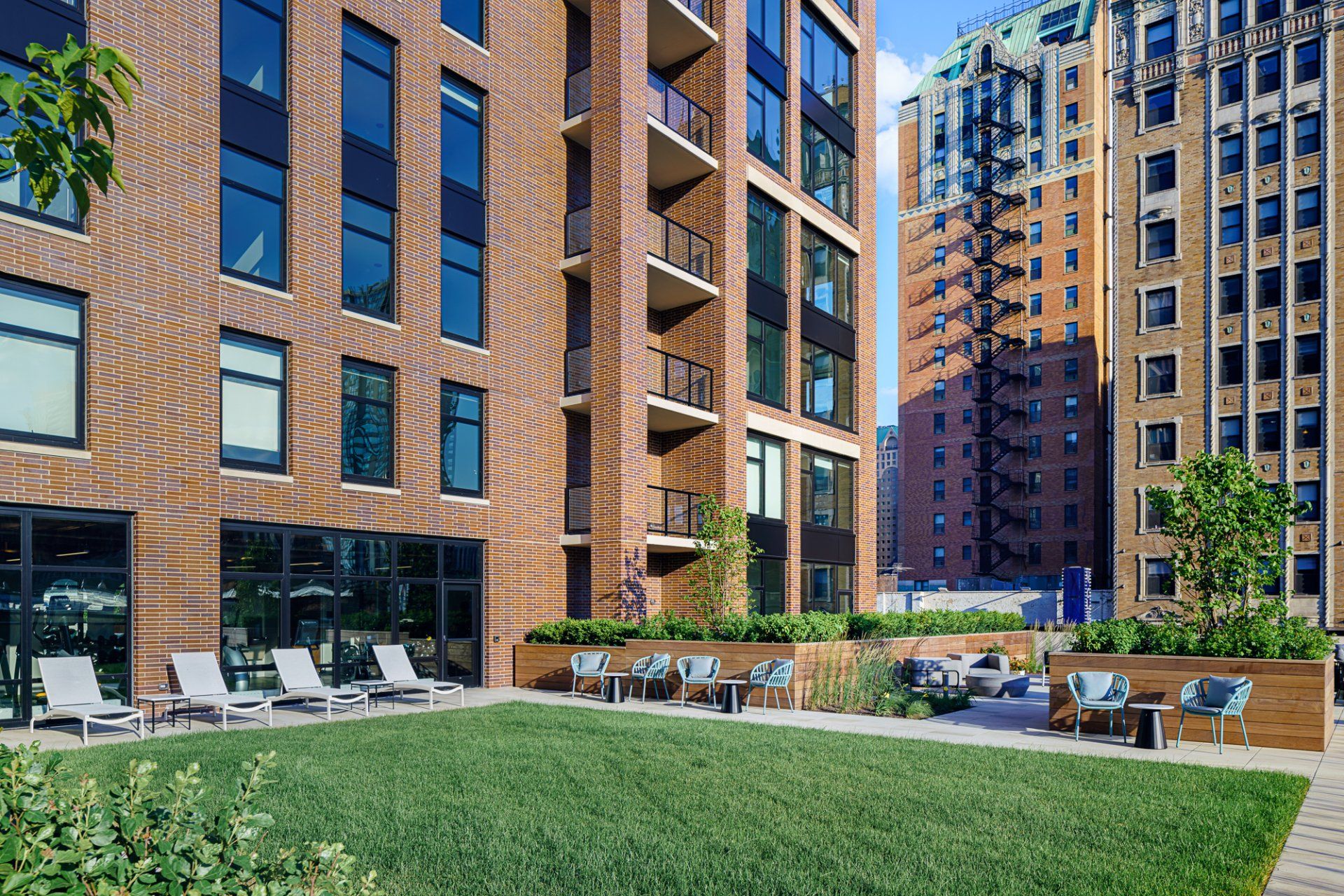 An exterior view of the apartment building at Gild Apartment with green space and seating areas.