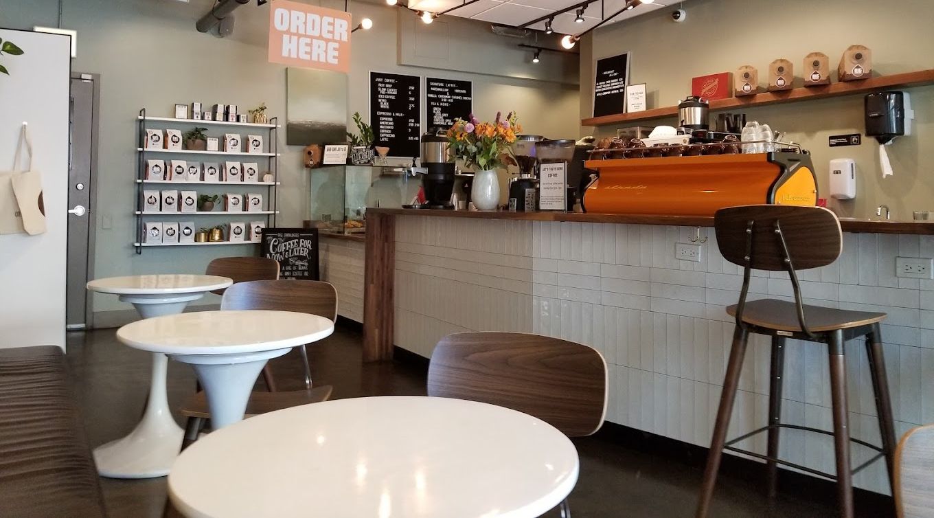 A restaurant with tables and chairs and a sign that says order here