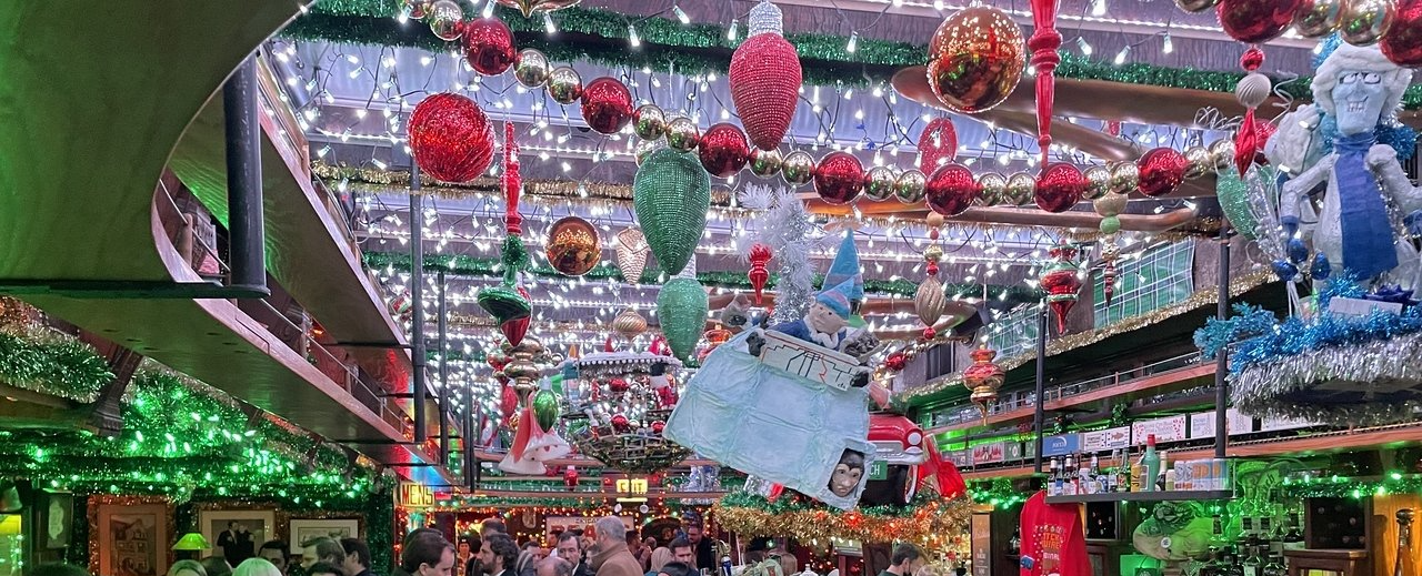 There are a lot of christmas decorations hanging from the ceiling of a building.