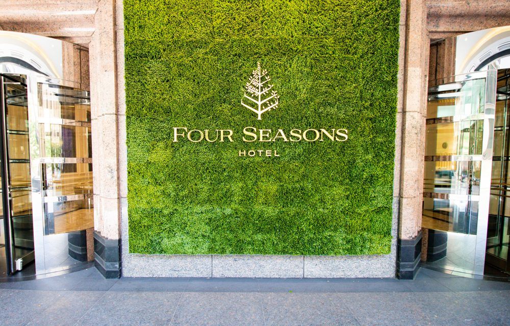 Four Seasons hotel entrance with green plant background.